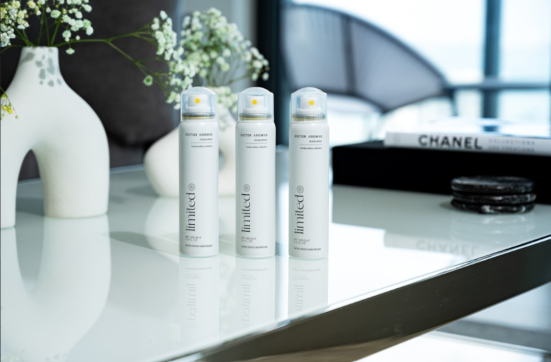 Three “Doctor Aromas” room sprays from the Limited collection displayed on a glossy white table, with minimalistic decor and a Chanel book in the background.