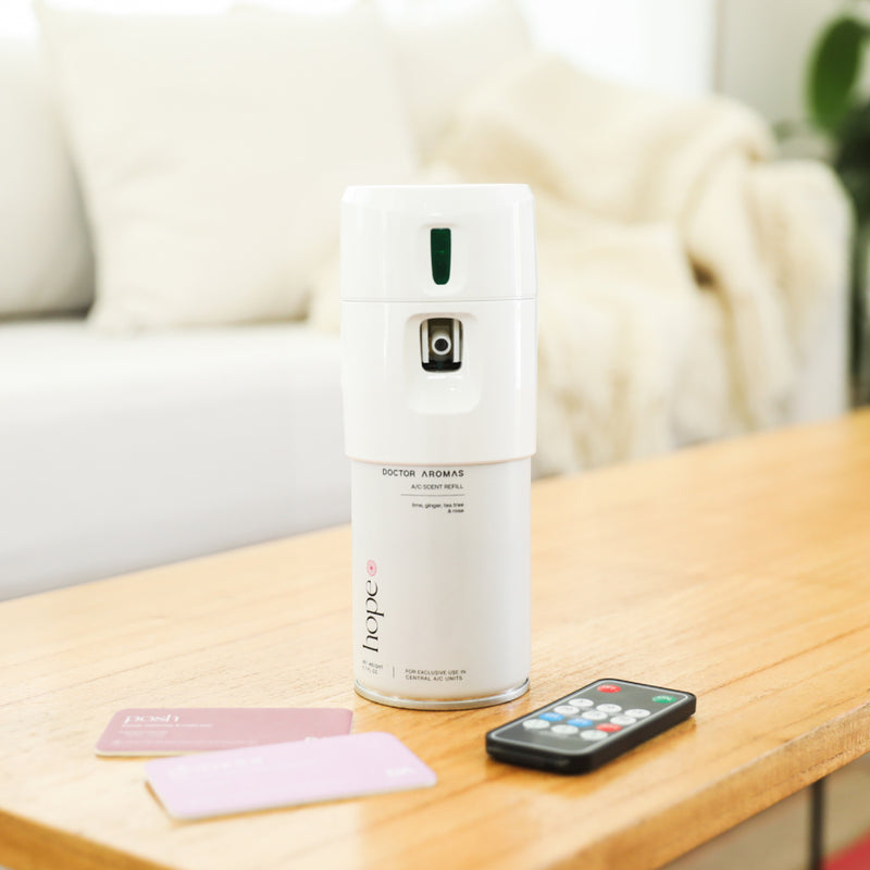 White cylindrical mini A/C scenting system with remote and two scent pads on wooden table. - Mini A/C Scenting System | Blush - Blush - Doctor Aromas