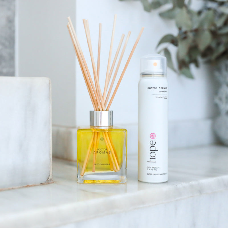 Glass reed diffuser bottle with yellow liquid and natural wooden sticks beside white spray bottle on marble surface. - Aroma Set | Holiday - Holiday - Doctor Aromas