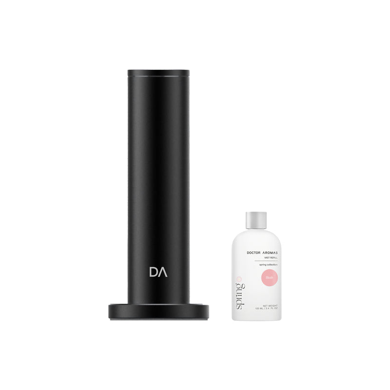Black cylindrical aroma diffuser with matte finish and round base next to a white scent bottle with pink label. - Aroma Diffuser 500 | Blush - Blush / Black - Doctor Aromas