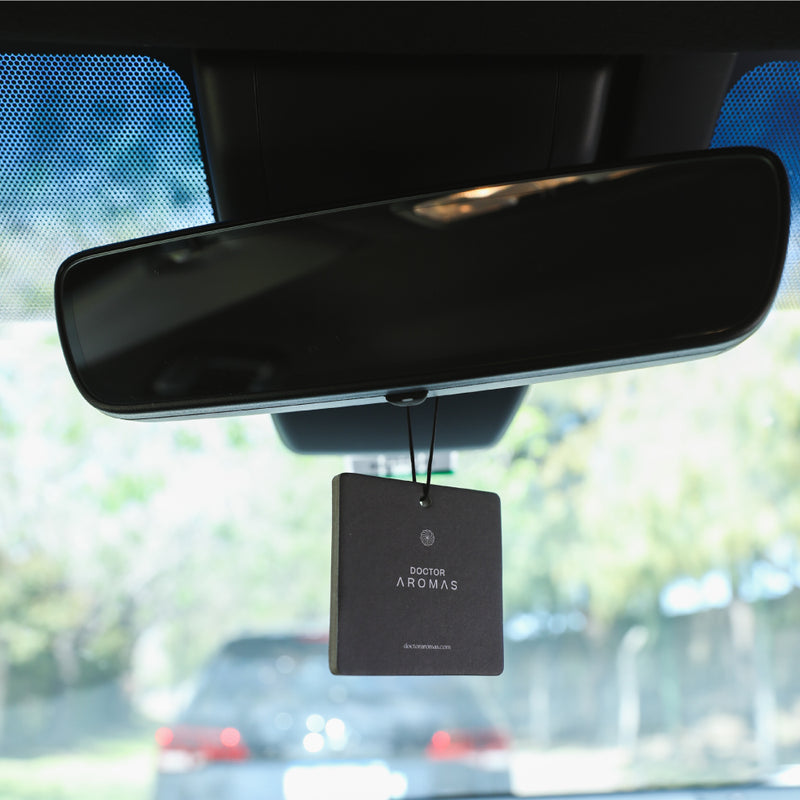 Black square pomelo-scented car perfume hanging from a rearview mirror with subtle embossed text. - Car Perfume | Pomelo - Pomelo - Doctor Aromas