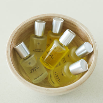 Wooden bowl filled with six yellow diffuser drop bottles with silver caps labeled Holiday Aromas. - Diffuser Drops | Holiday - Holiday - Doctor Aromas