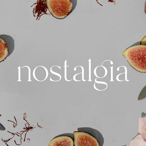 Gray background with sliced figs and pink flower petals surrounding the white Nostalgia logo. - Portable Scent Diffuser | Nostalgia - Nostalgia / Black - Doctor Aromas