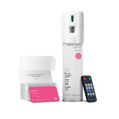 White cylindrical A/C scenting system with green indicator and black remote control beside it, next to a white box with pink . - A/C Scenting System | Pomelo - Pomelo - Doctor Aromas