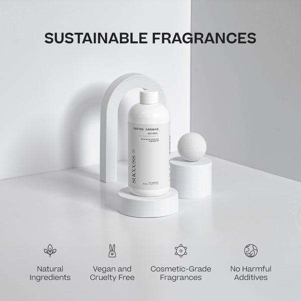 Two white cylindrical mist refill bottles with minimal black and orange text on a white stand, labeled Sustainable Fragrances. - Mist Refill Twin Pack | Success - Success - Doctor Aromas